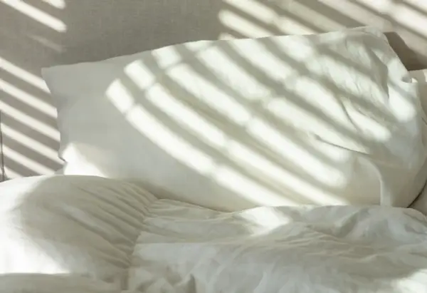 Cama con sábanas y almohadas blancas